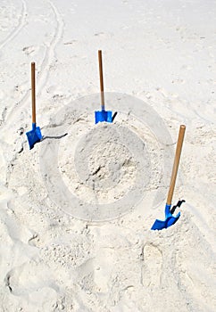 Bright white sand at beach with three shovels for making sand castles on a relaxing day