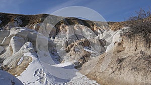 Bright white snow covers ground around interesting geologic site.