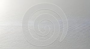 Bright white textured paper surface with subtle grain and soft, diffused lighting
