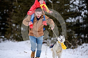 Bright winter day dad with daughter in the woods with their dog, fun walk in the snowy forest