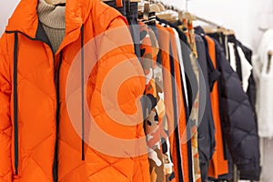 Bright women`s clothes on hangers in the store. Jackets, jumpers and blouses. Close-up