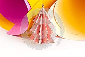 Bright wooden pink Christmas tree on colorful magenta and yellow paper swirls abstract background with copy space. Simple New Year