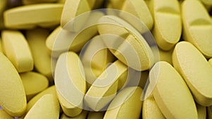 Bright yellow antibiotics and antiviral pills lie together and rotate closeup