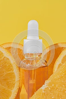 Bright yellow background with a dropper bottle of citrus infused face serum with vitamin C and fresh orange slices