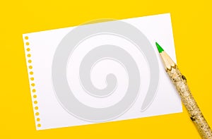 On a bright yellow background, a large wooden pencil and a white sheet of paper with a place to insert text