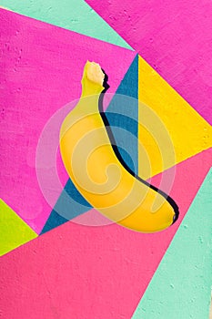 Bright yellow banana on geometric background of wall with bright tones. photo
