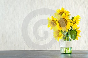 Bright yellow big sunflowers in glass vase on dark table on light texture background. Mockup banner with sunflower bouquet with c