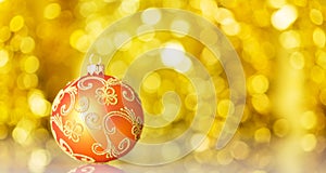 Bright yellow Christmas ball with beautiful decoration on yellow background with bokeh effect