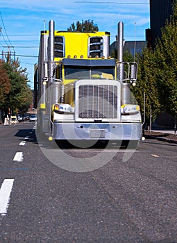 Bright yellow classic big rig semi truck with freezer semi trail