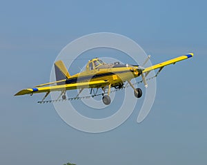 Bright yellow crop duster airplane soaring across a pristine blue sky