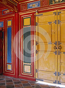 Bright yellow doors against a colourful red, blue and green wall with golden details