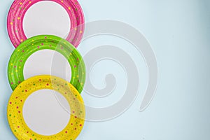 Bright yellow, green and pink paper plates on a blue background.