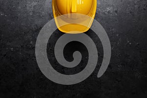 Bright yellow hard hat on dark black background. Contractor or Under Construction background