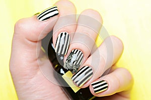 Bright yellow manicure with black stripes and sunflowers pattern on yellow background