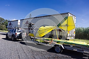 Bright yellow microlight aircraft on car trailer
