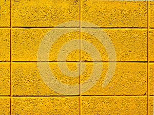 Bright yellow painted cinder block wall background photograph.