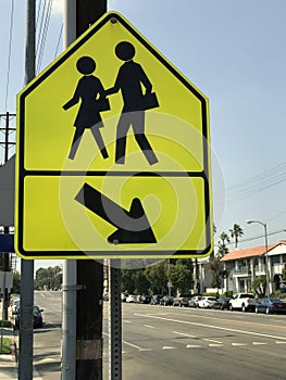 Bright Yellow Pedestrian Crosswalk Sign Next to a Major Road