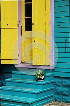 Bright yellow shutters frame a yellow door in a blue Creole cottage, New Orleans.