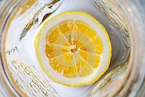 Bright yellow sliced lemon at the bottom of an empty glass mug. Lemonade ingredients for breakfast on a sunny morning