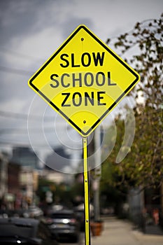 Bright Yellow Slow School Zone Sign on an Urban Street During the Day