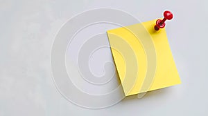 Bright yellow sticky note on a gray background pinned by a red pushpin. Minimalistic composition, ideal for reminders