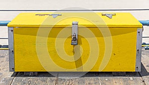 Bright yellow wood trunk box locked with rusty padlock