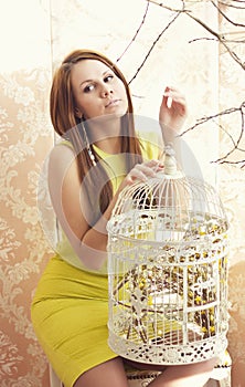 Bright young pretty woman posing with a cage