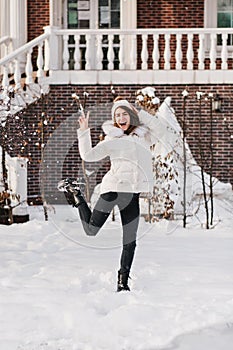 Brightful true emotions of excited stylish woman having fun in snow on street in cold winter time. Smiling, jumping