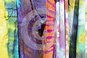 Brightly colored boho tie dyed garments hanging together - background - selective focus