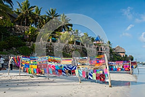 Brightly colored fabric for sale on a white sand beach against a beautiful blue sky