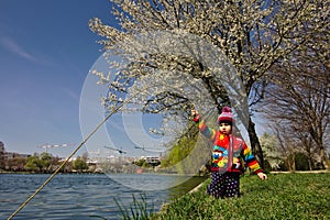 Brightly colored girl pretends to be fishing under a blossoming tree