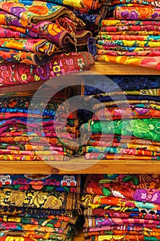 Brightly colored handwoven textiles stacked on a shelf in Merida, Mexico