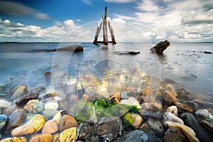 Brightly colored rocks and green underwater seaweed seen through the crystal clear waters of harbor port at lake