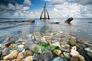 Brightly colored rocks and green underwater seaweed seen through the crystal clear waters of harbor port at lake