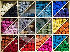 Brightly colored skeins of wool organized by color on triangular shelves