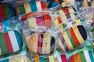 Brightly coloured favored cheese wrapped for sale at a market