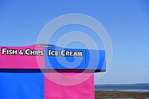 Brightly coloured pink and blue Ice cream and fish & chips and donuts kiosk on Southend on Sea