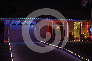 Brightly illuminated christmas decorations on front yard driveway of florida family home garage. Outside decor for