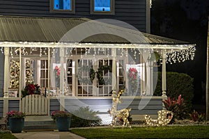 Brightly illuminated christmas decorations on front yard porch of florida family home. Outside decor for winter holidays