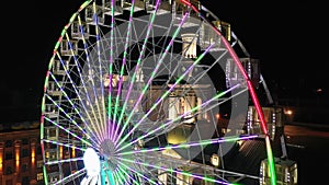 Brightly lit ferris wheel ride spinning at night at a carnival, amusement park, theme park, fair, thrill park.