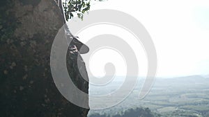 Brightly lit young female climber playing smart phone while sitting on cliff  thai language on shirt is i`m climber