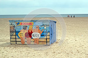 A brightly painted deck chair hut on a beach.