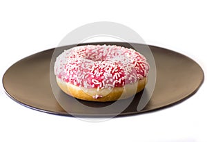 Brightly pink donut on a black ceramic plate on white background