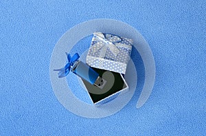 Brilliant blue usb flash memory card with a blue bow lies in a small gift box in blue with a small bow on a blanket of soft and fu