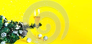 Brilliant Christmas decor. Filled glass of champagne decorated in festive theme on yellow background, closeup, copy