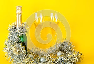 Brilliant Christmas decor. Filled glasses and bottle of champagne decorated in festive theme on yellow background