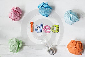 Brilliant and original idea suggested by glowing light bulb and crumpled paper against white background