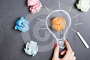 Brilliant and original idea suggested by glowing light bulb in womanâ€™s hand and crumpled paper against white background