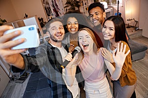 Bring on the evening. Group of young happy multicultural friends posing for selfie while spending time together, playing