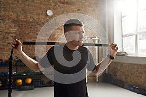 Bring the focus on fitness. Sportive man looking aside, using pilates exercise body stick or bar while having workout at